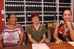 Drei Frauen sitzen nebeneinander an einem Tisch.